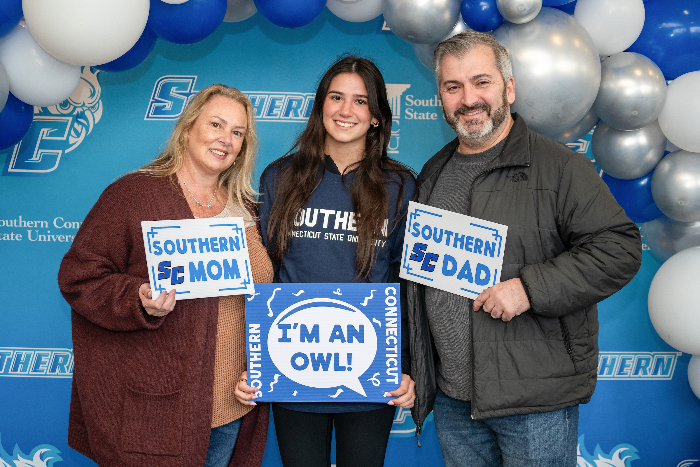 Student and parents holding cards that indicate they're proud